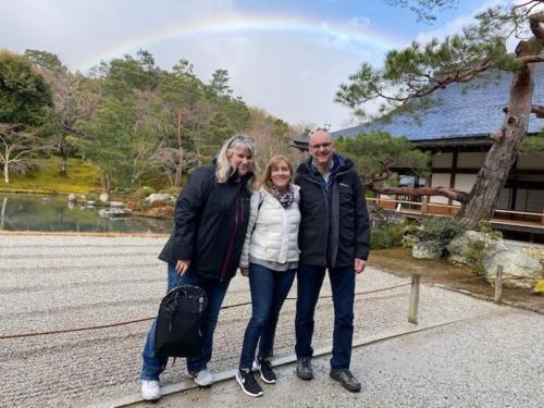 Three people in front of a rainbow